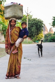Kobieta-z-dzieckiem-na-reku,-psem-i-torba-na-glowie-na-ulicy-w-Orchha-Indie