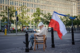 The-old-man-with-flag-sitting-on-his-own-chair-at-MarszaÅkowska-street-in-Warsaw-after-KOD-March-